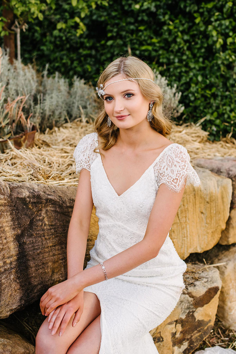 Boho bride sitting outside with gorgeous lace wedding gown.