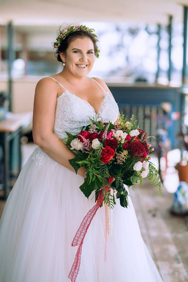 Bride with wedding hair flowers holding a large bouquet.