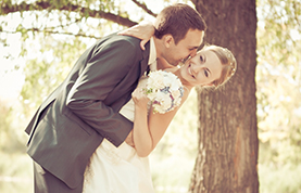 Groom bending over to kiss Bride.