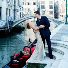 Photo of a Groom holding his Bride near a Gondola in a canal.