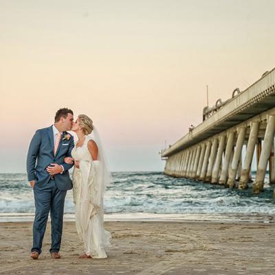 Bride and groom kissing next to pier at Surfers Paradise beach.