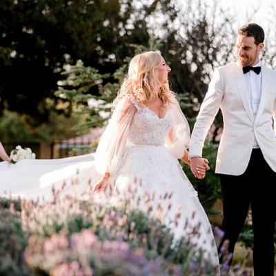 Groom in stylish White jacket and Black bowtie and pants walking with his beautiful Bride in White. 