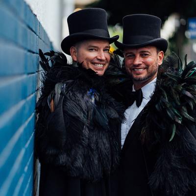 Brad and Scott getting married at Broadway Chapel, smiling in top hats and feathers.