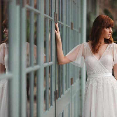 Bride in a wedding gown with flounced sleeves and flowing skirt.