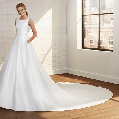 Model posing in room, wearing a crisp white bridal gown from Rosa Clara.