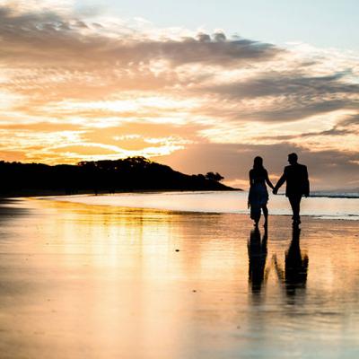 Couple walking along Stradbroke Island beach at sunset.