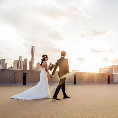 Bride and Groom walking holding hands with a view of the city.